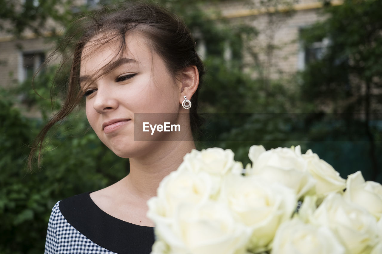 Teenage girl sun bouquet of white roses outdoors portrait