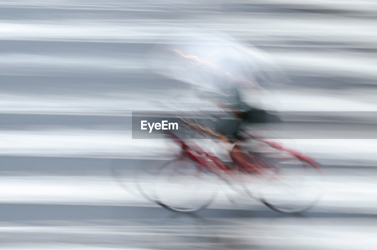 BLURRED MOTION OF PEOPLE RIDING BICYCLE ON ROAD