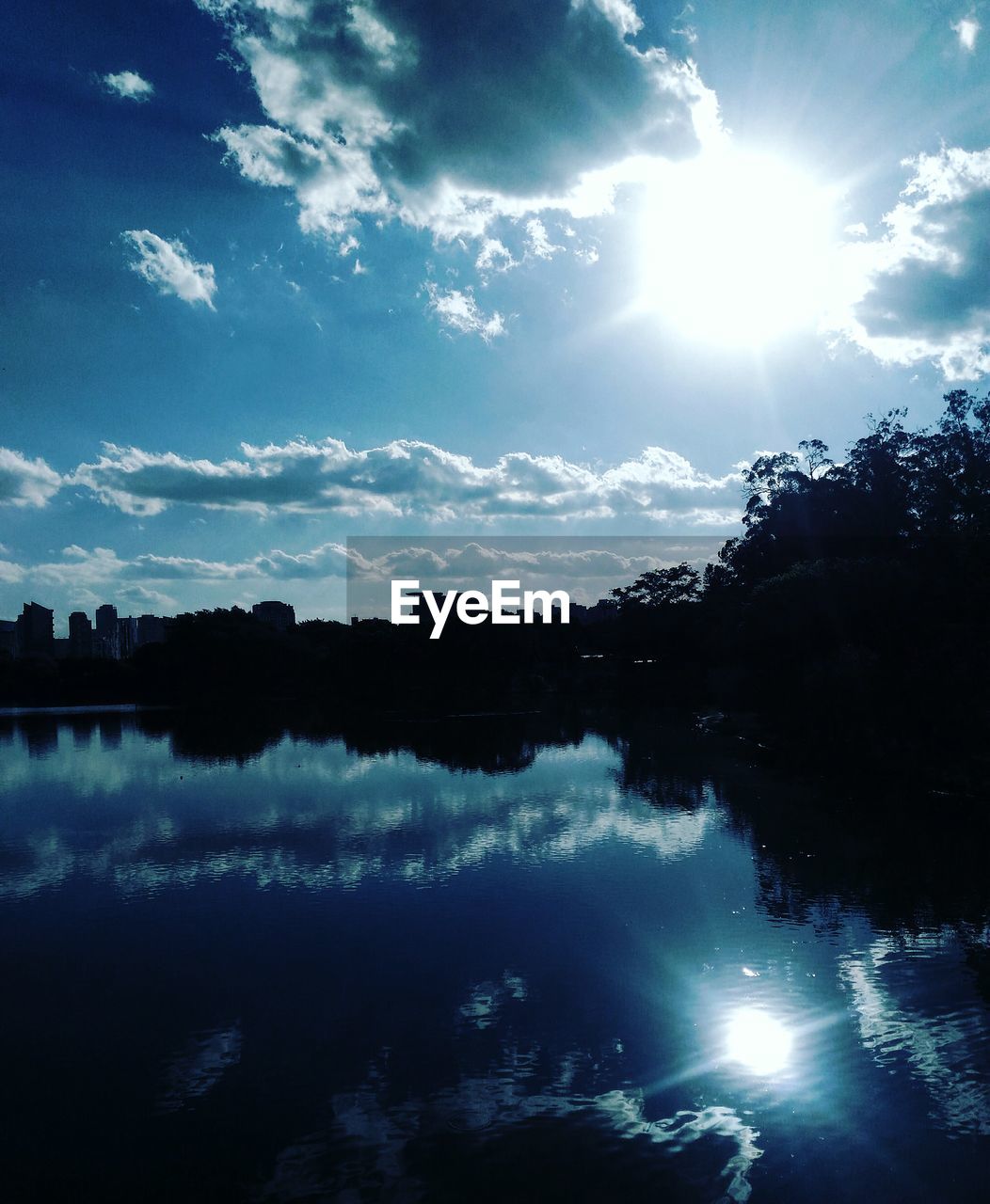 Reflection of silhouette trees in lake against sky