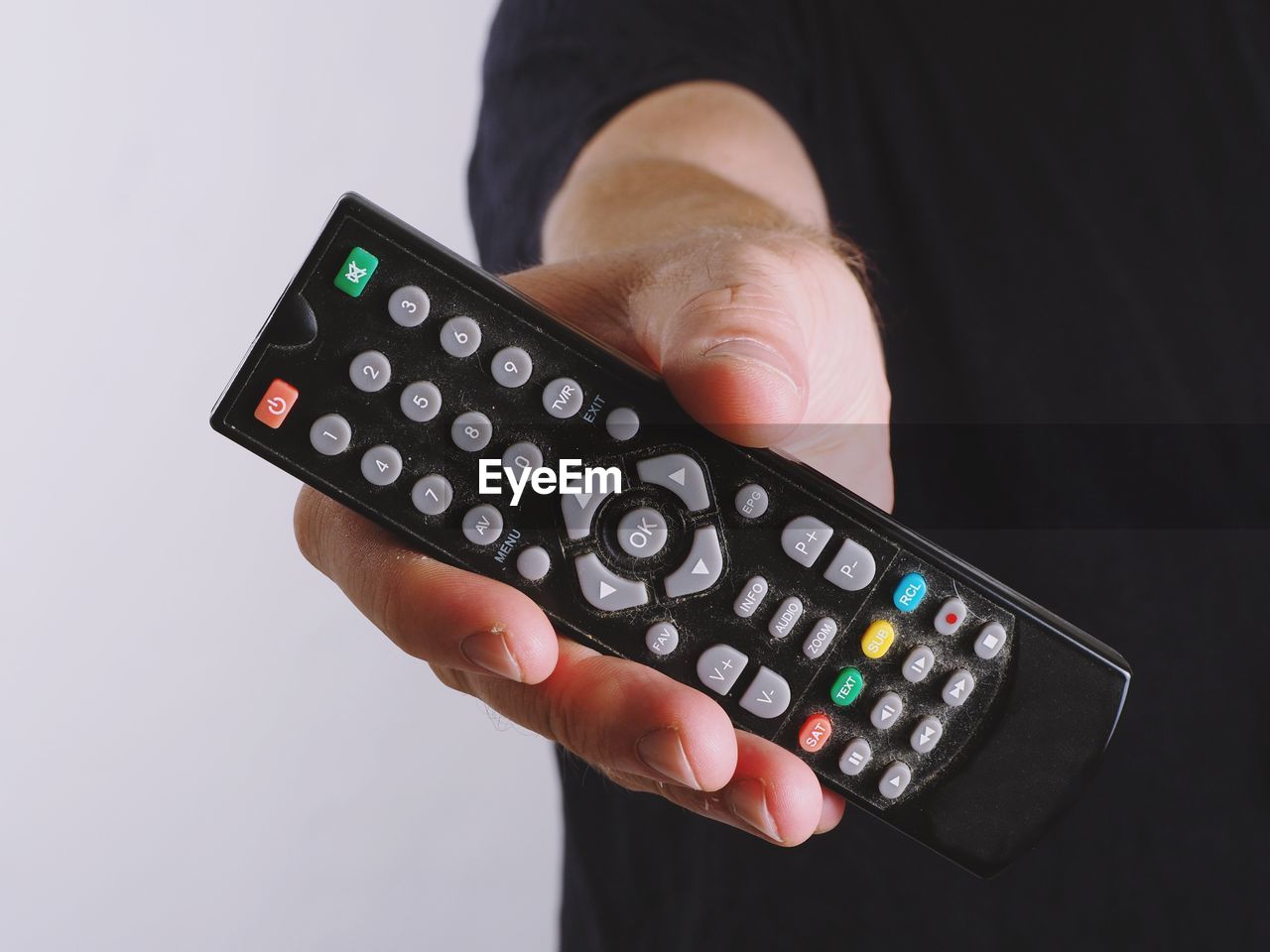 Midsection of man showing remote control against white background