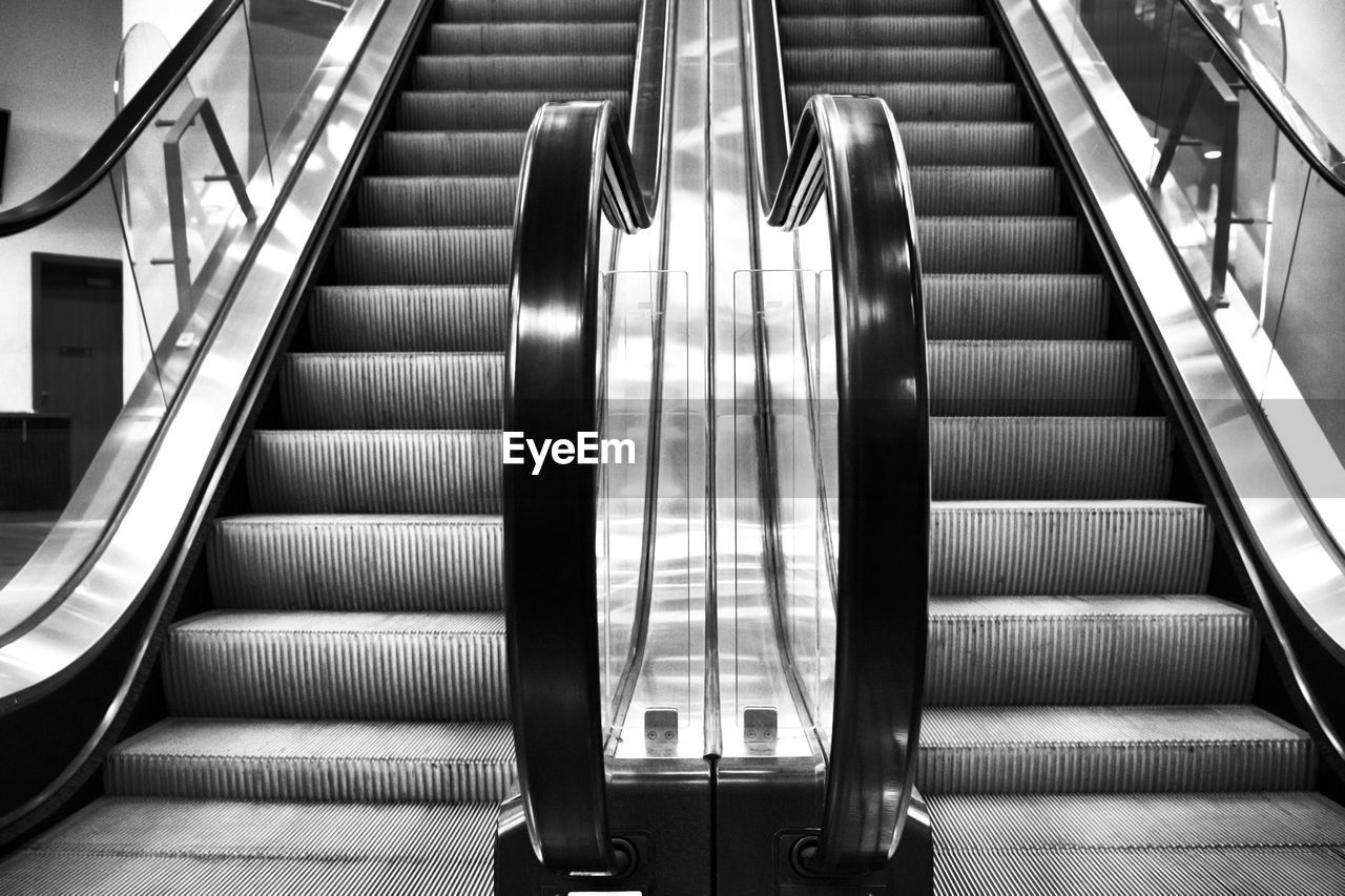 escalator, staircase, steps and staircases, railing, architecture, black and white, convenience, monochrome, stairs, indoors, monochrome photography, black, built structure, the way forward, technology, futuristic, subway station, low angle view, transportation, white, no people, transport, line, motion, moving walkway, metal, subway, illuminated, public transport
