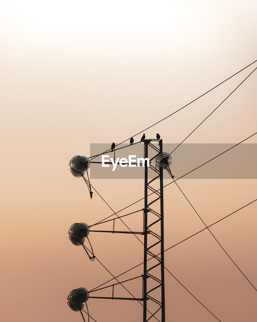 Low angle view of electricity pylon against clear sky during sunset