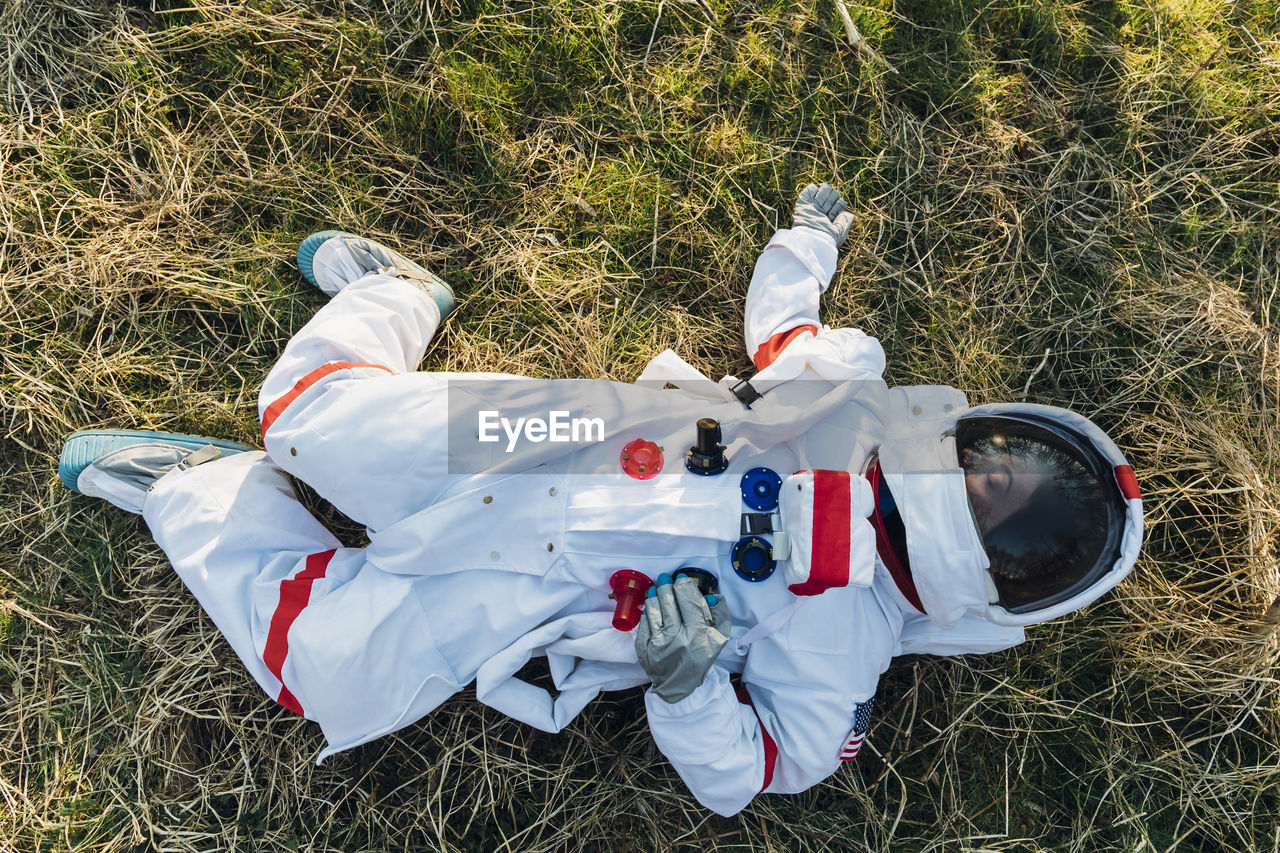 Female astronaut lying on land in forest