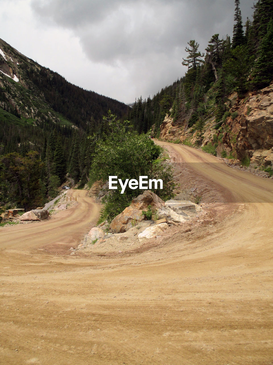 Empty road leading towards mountain against cloudy sky