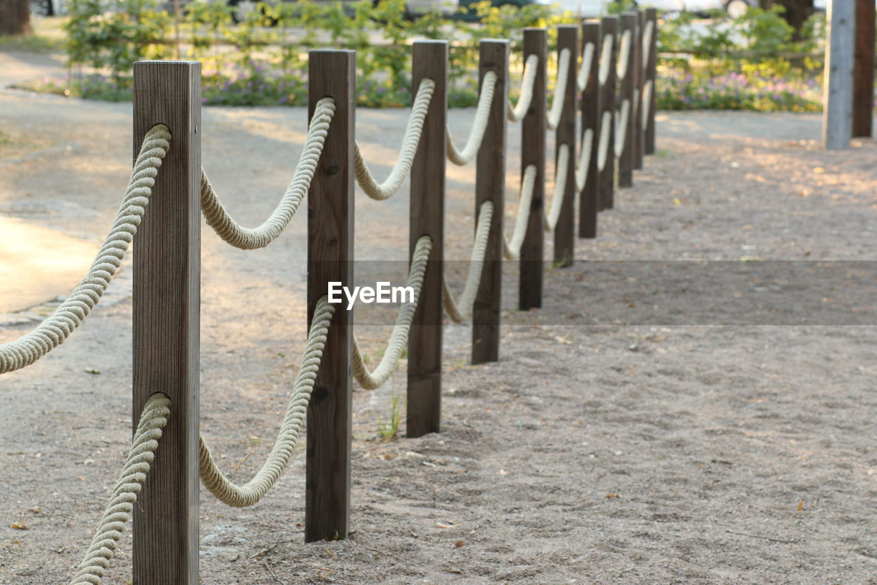 Wooden post on footpath by fence