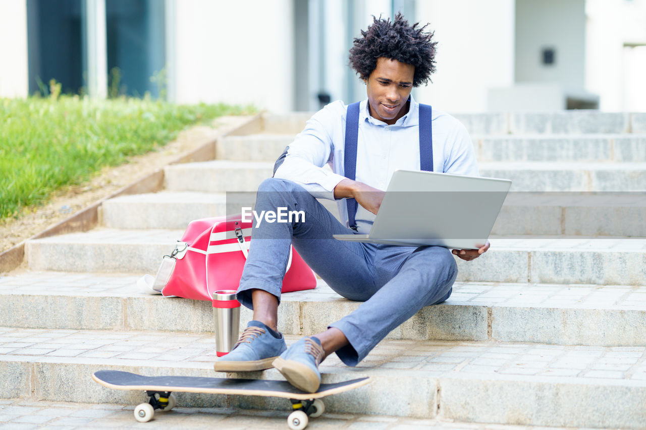 Young man using mobile phone while sitting on staircase