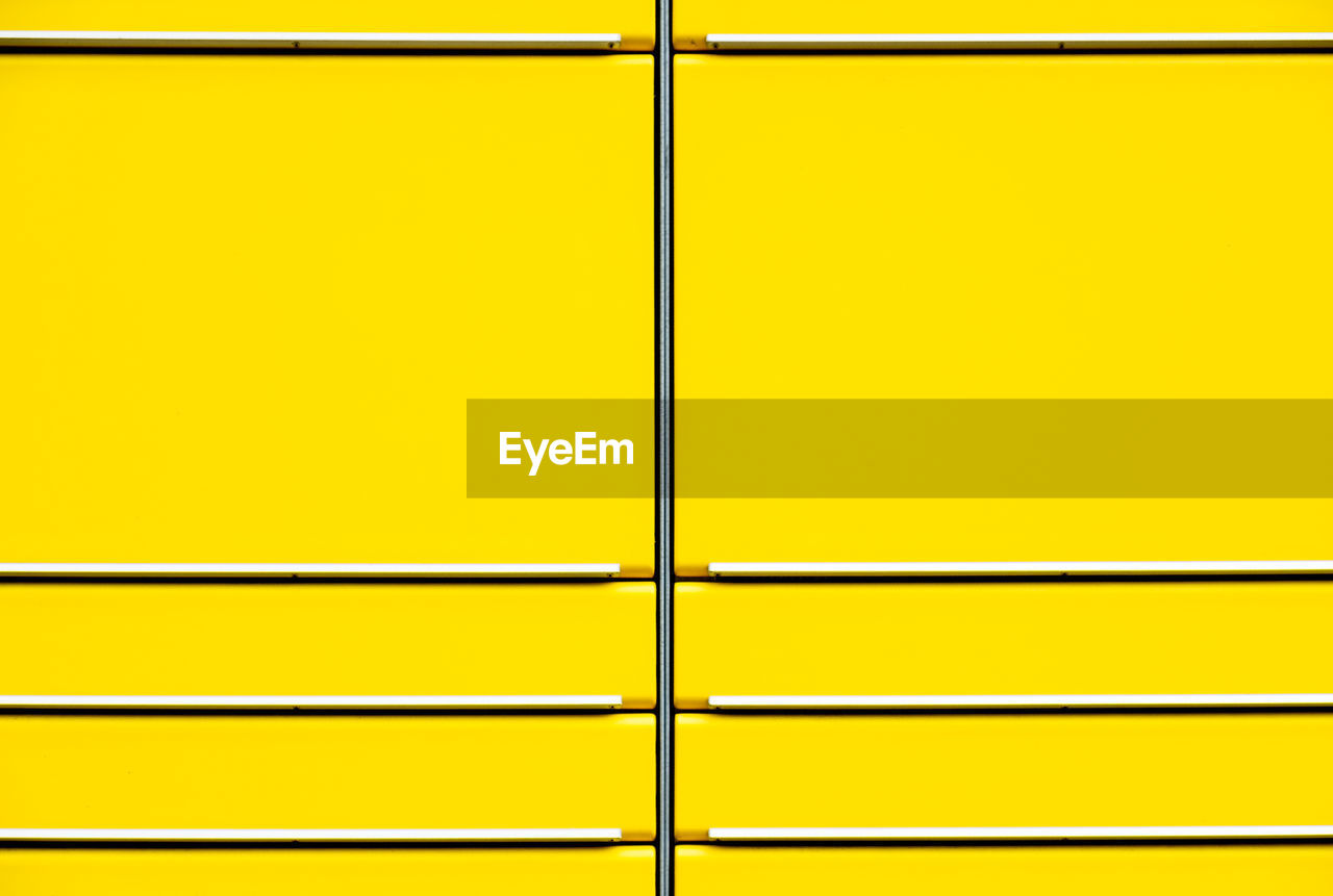 Full frame shot of yellow wall seen through metal grate