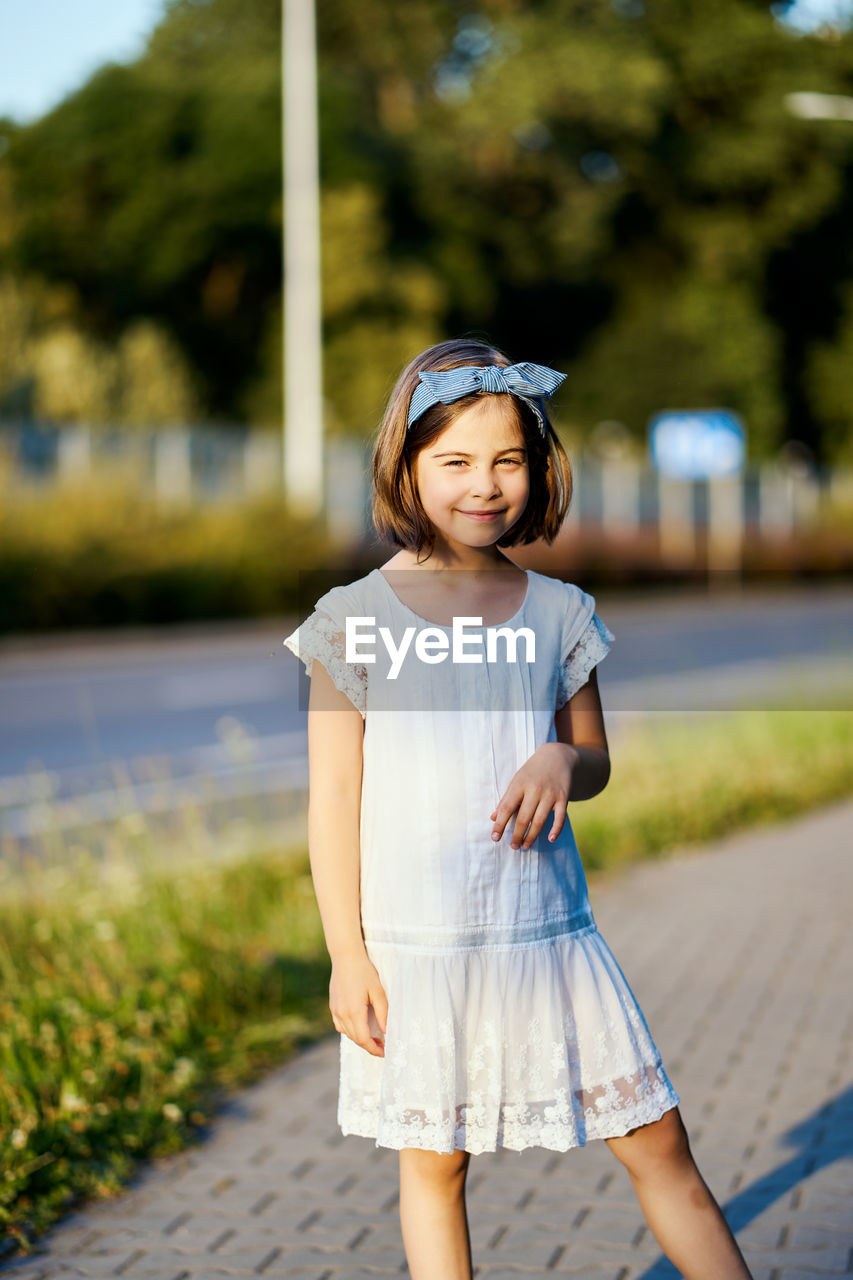 Portrait of girl standing on footpath in park