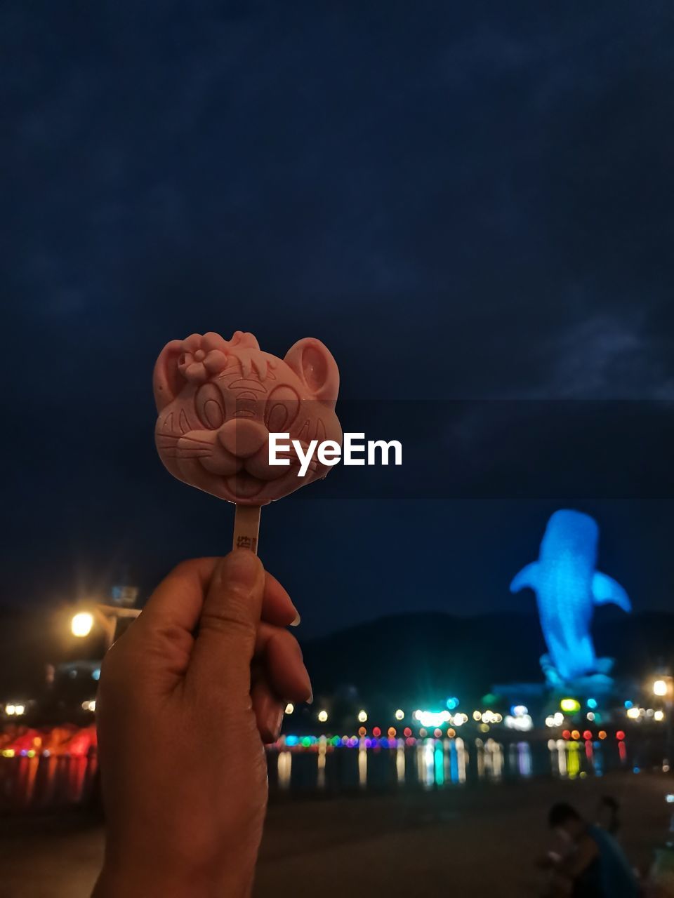 hand, sky, night, holding, illuminated, cloud, celebration, light, emotion, positive emotion, city, nature, blue, lighting, food and drink, architecture, one person, sweet food, personal perspective, event, adult, sweet, outdoors, love, focus on foreground, lighting equipment, food, heart shape