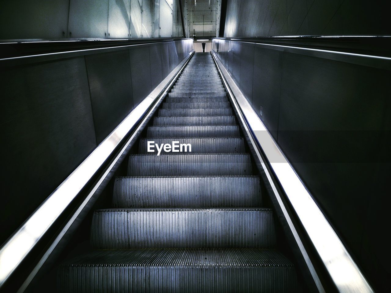 LOW ANGLE VIEW OF ESCALATOR IN ILLUMINATED STAIRCASE