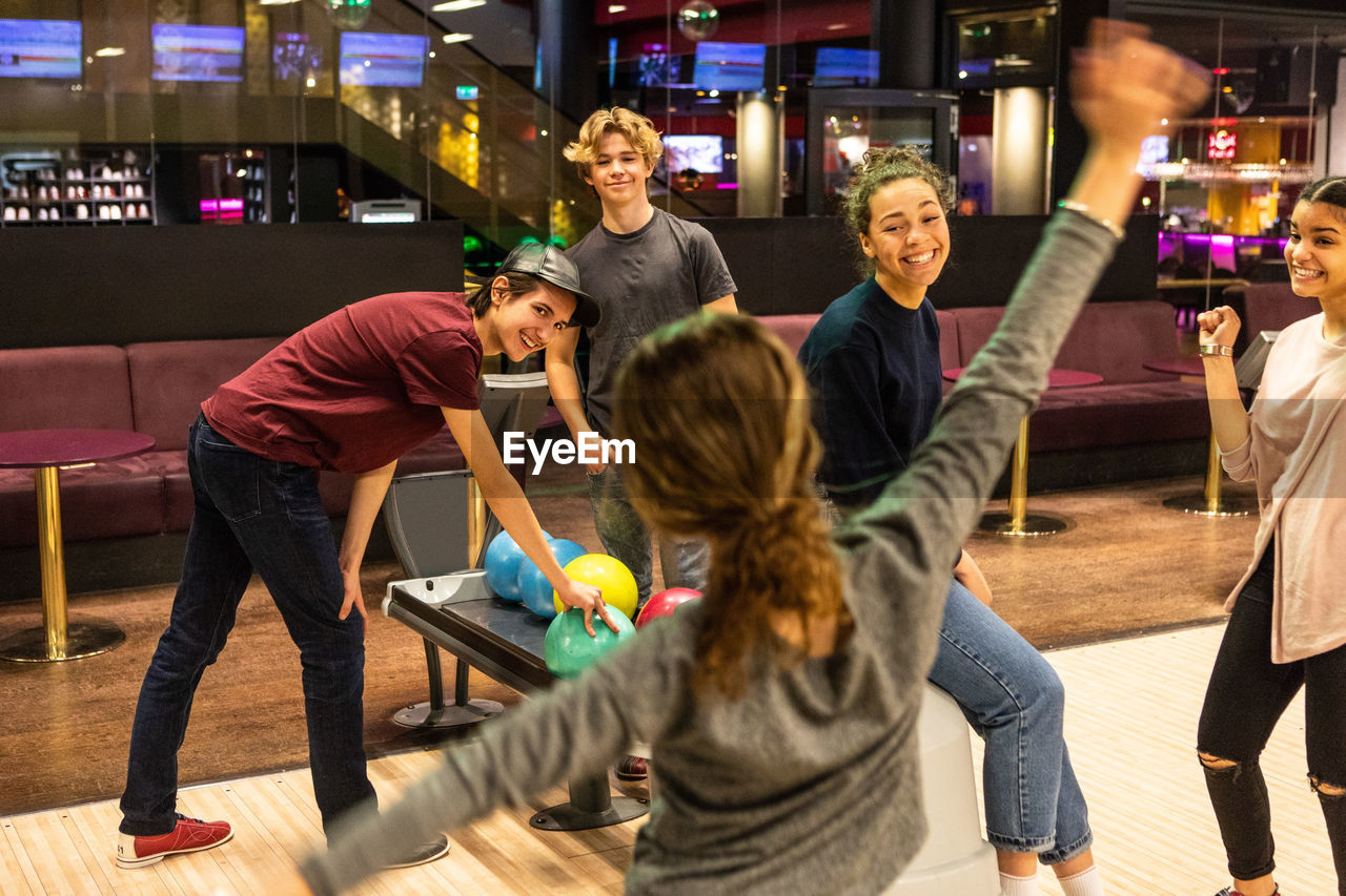 Cheerful multi-ethnic teenagers enjoying at bowling alley