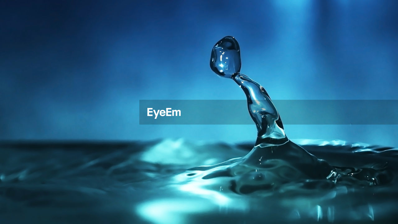 CLOSE-UP OF DROP ON RIPPLED WATER IN SUNLIGHT