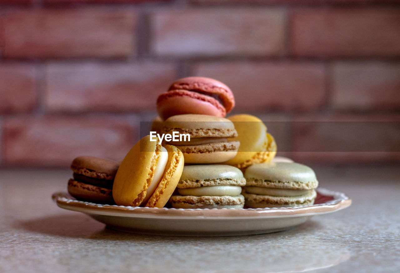 Plate of french macarons in front of a brick wall in the kitchen