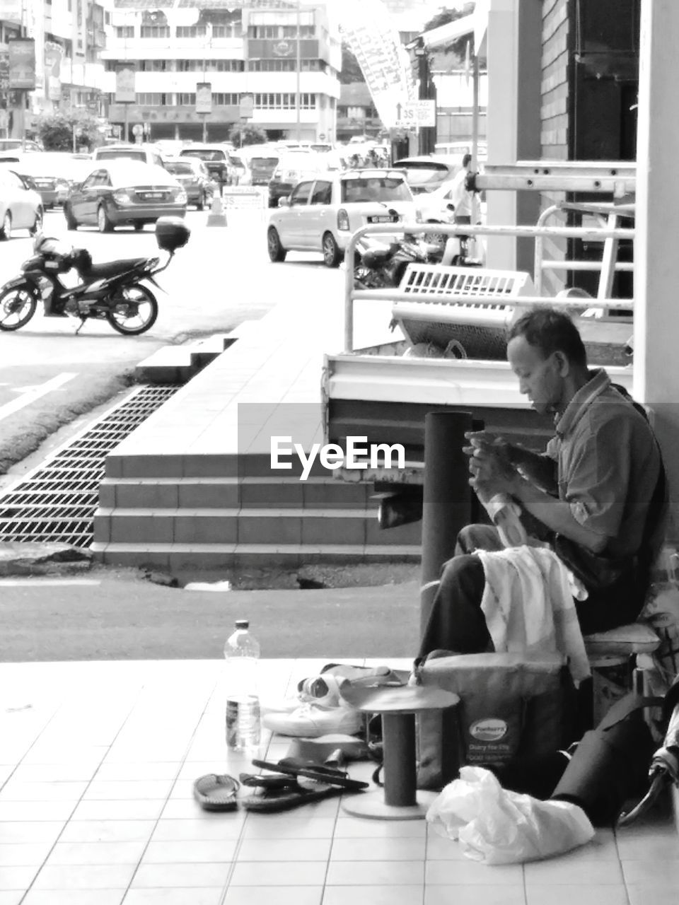 MAN SITTING ON STREET IN CITY