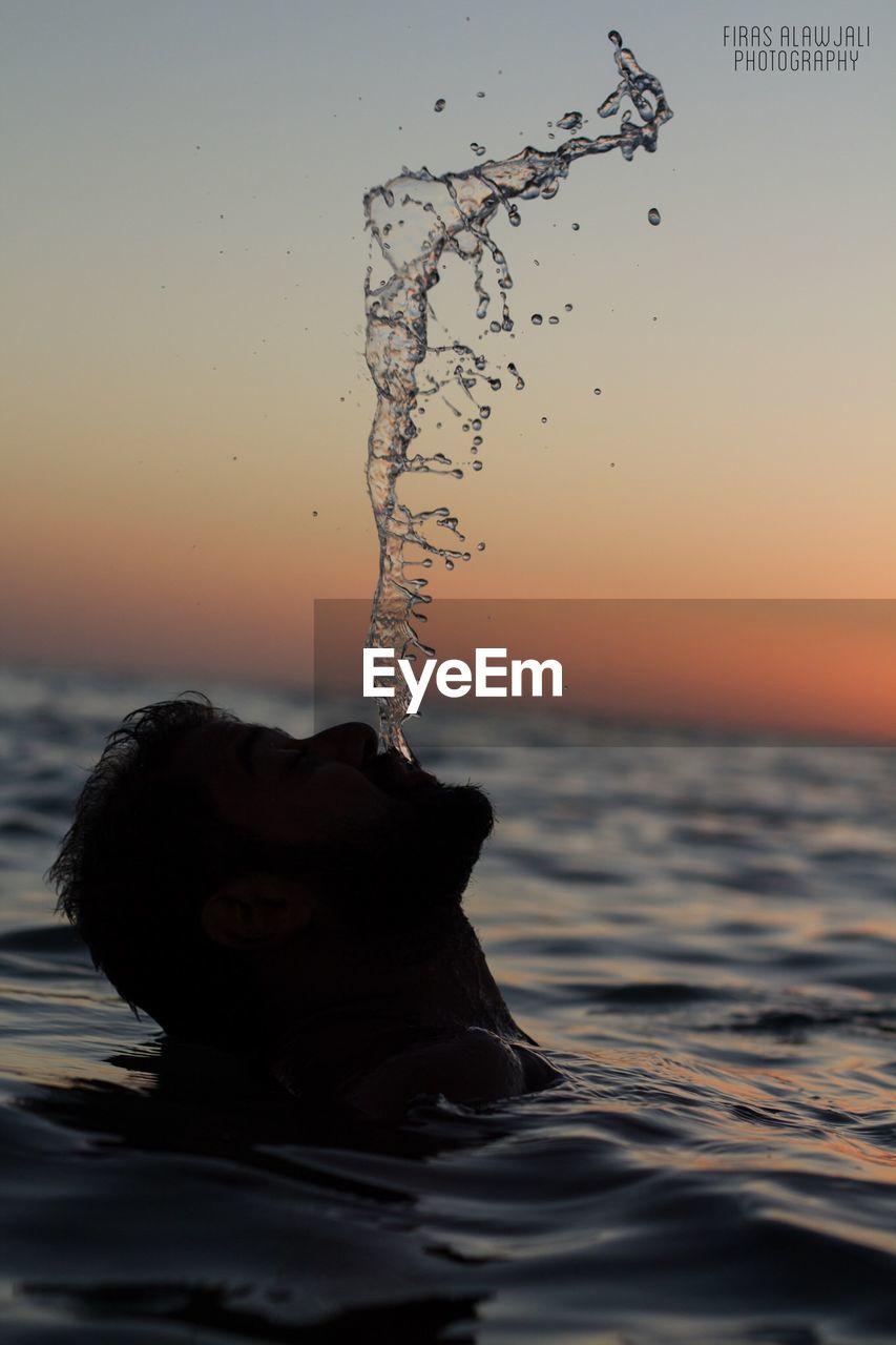 CLOSE-UP OF SPLASHING WATER AT BEACH DURING SUNSET