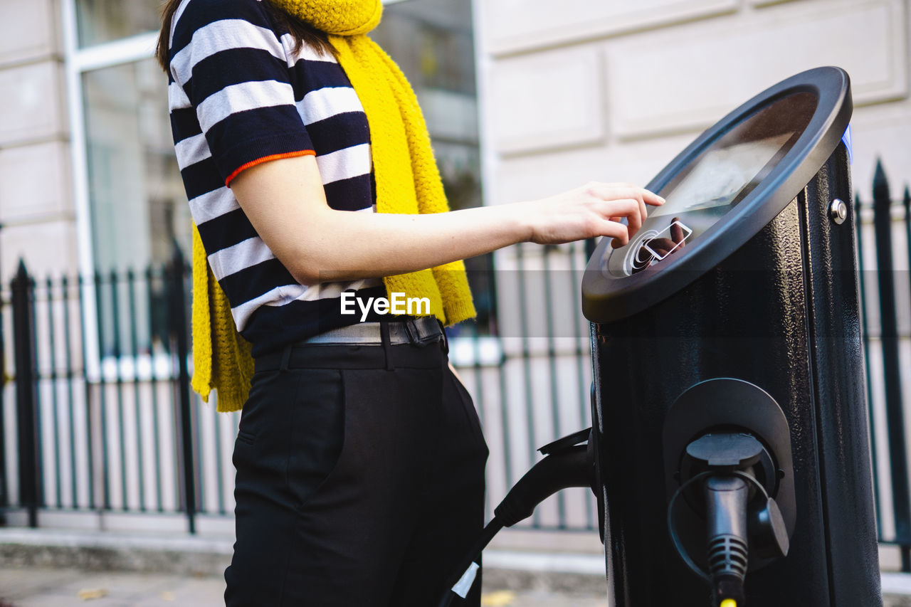 Woman using kiosk at electric charging station