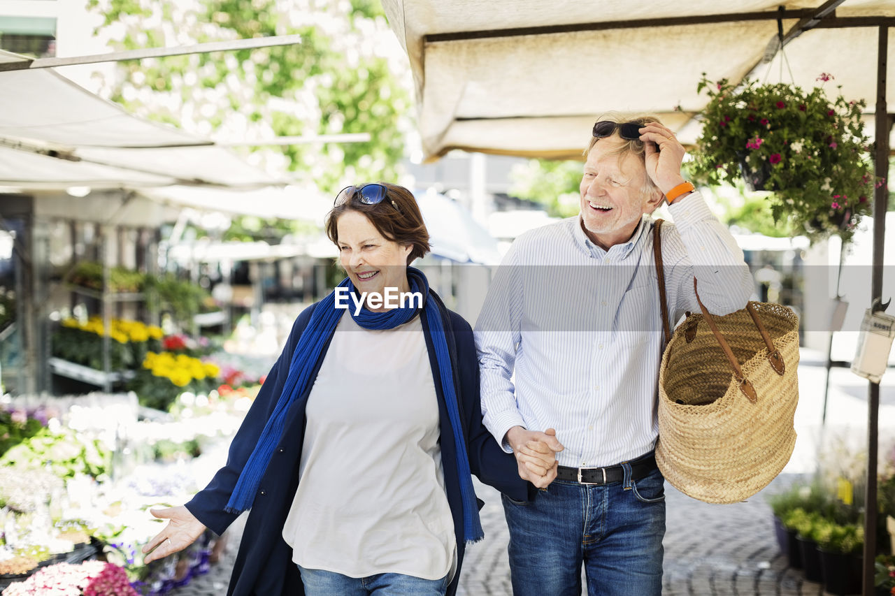 Happy senior couple walking at flower market