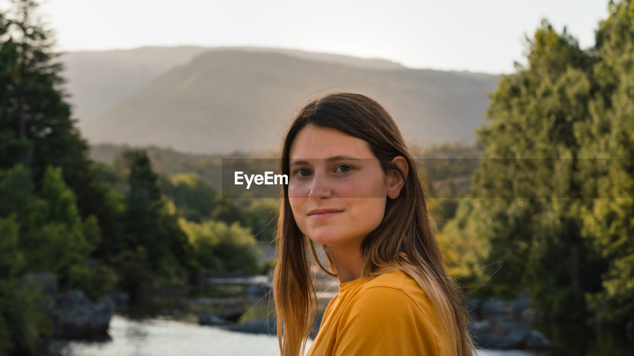 Portrait of young woman against trees