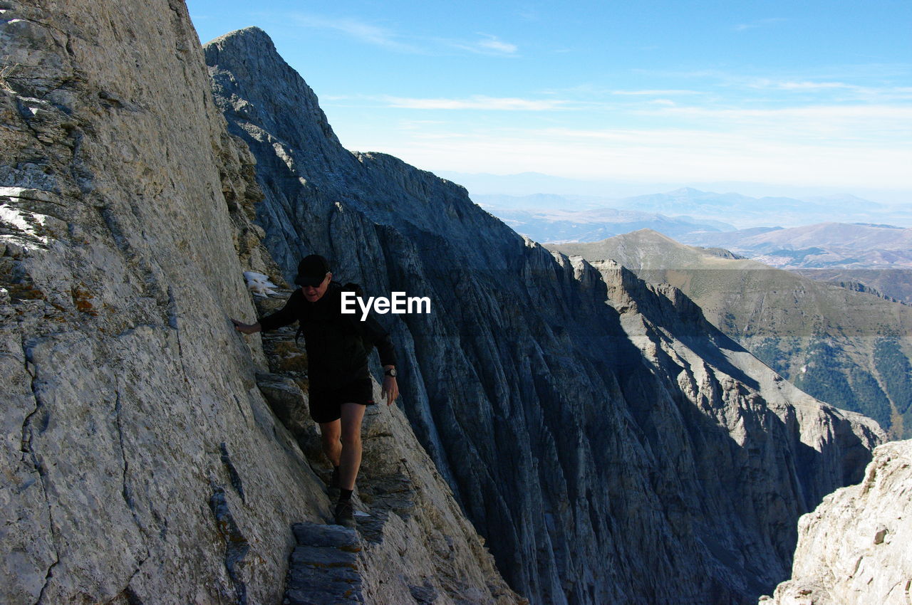 Senior man climbing on rocky mountains