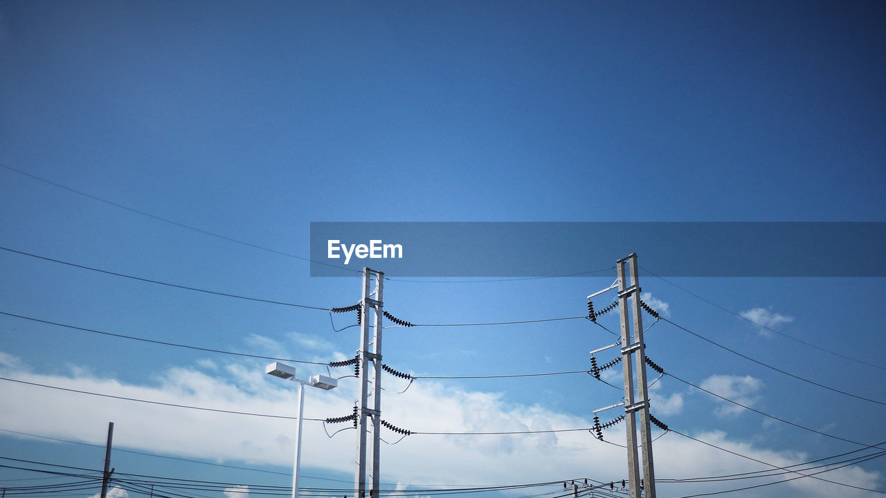 Low angle view of electricity pylon against blue sky