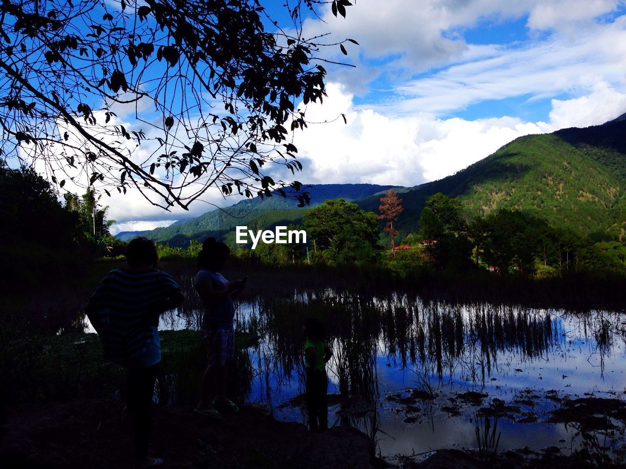 Scenic view of lake and mountains against cloudy sky