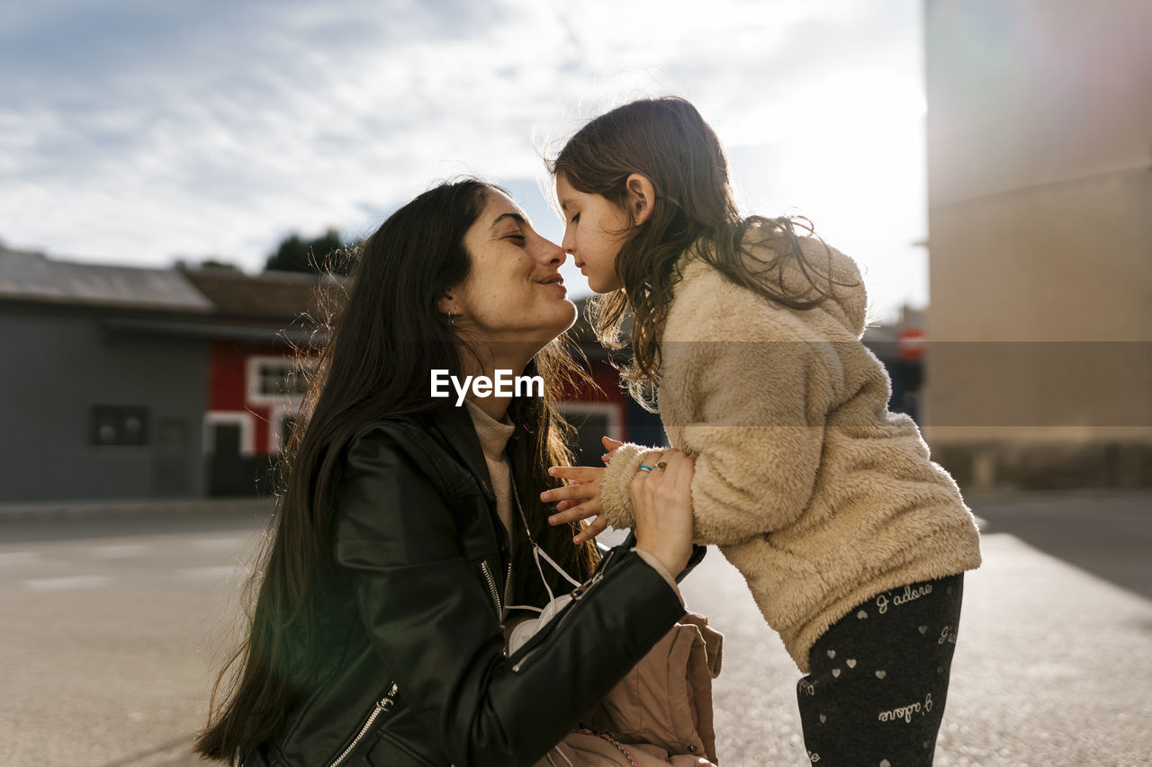 Daughter rubbing nose with mother while standing on road