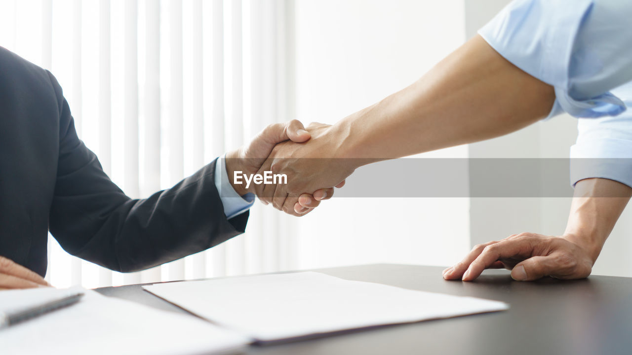 midsection of business colleagues shaking hands at office