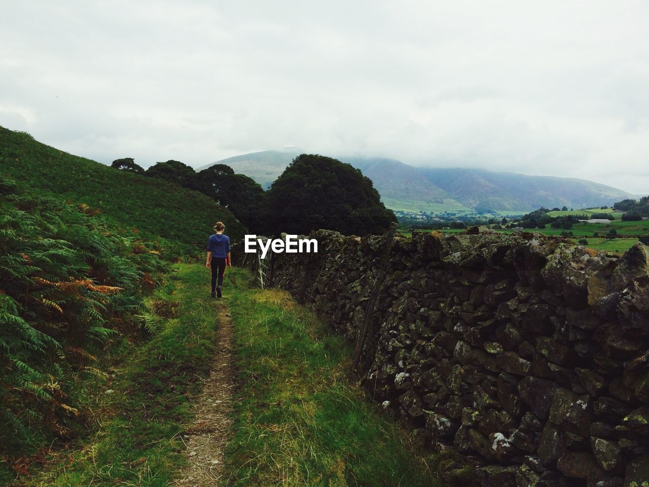 REAR VIEW OF MAN WALKING ON MOUNTAIN