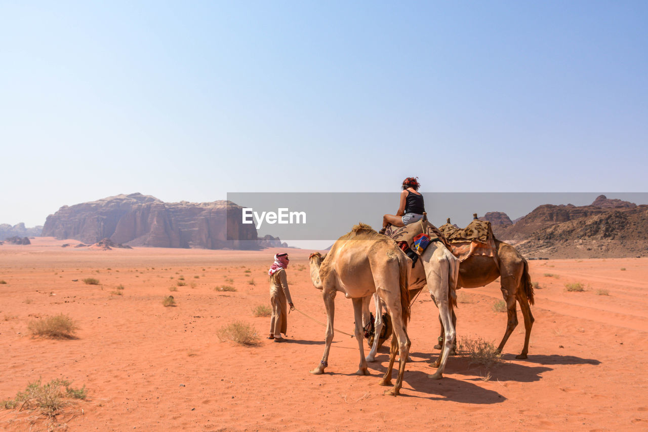 MEN RIDING HORSES ON DESERT