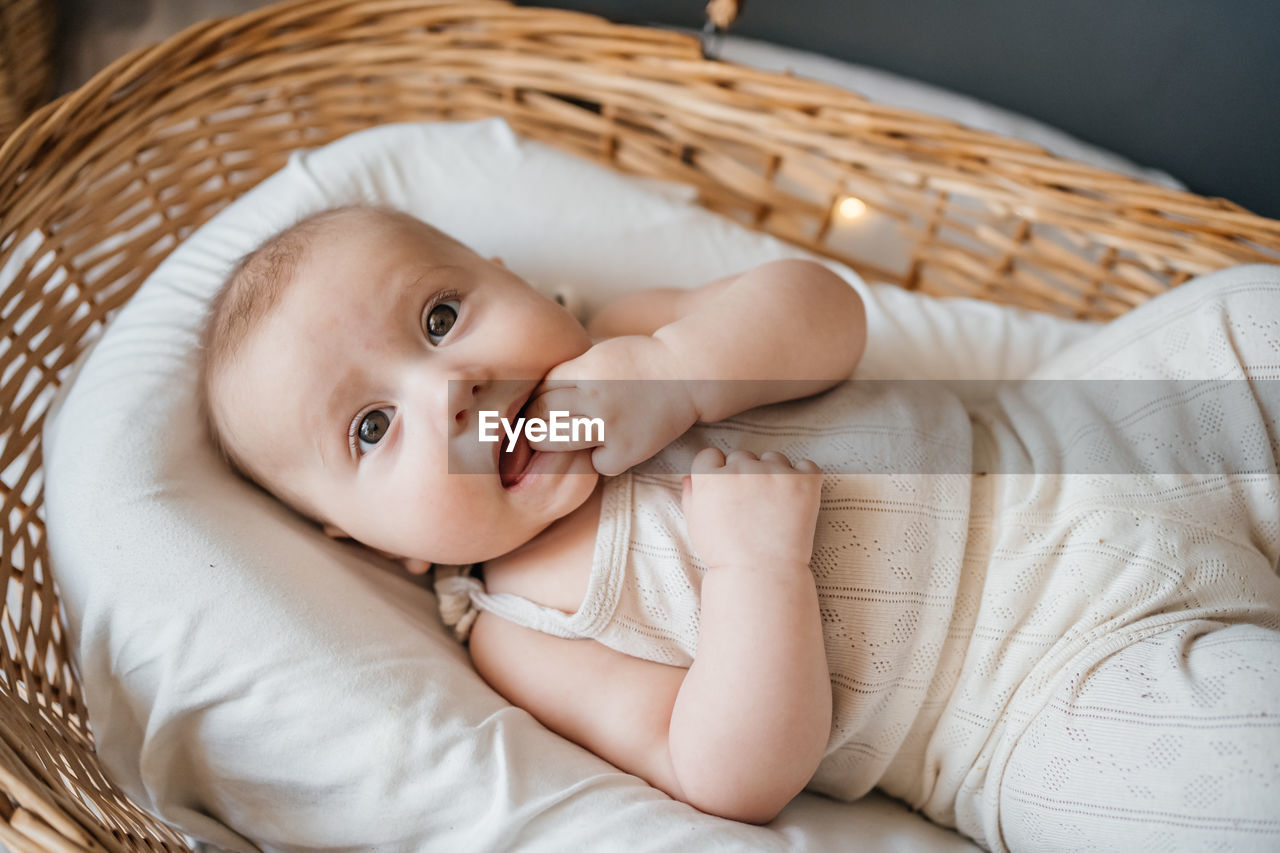 Baby lies in a wicker basket gray background willow eco style