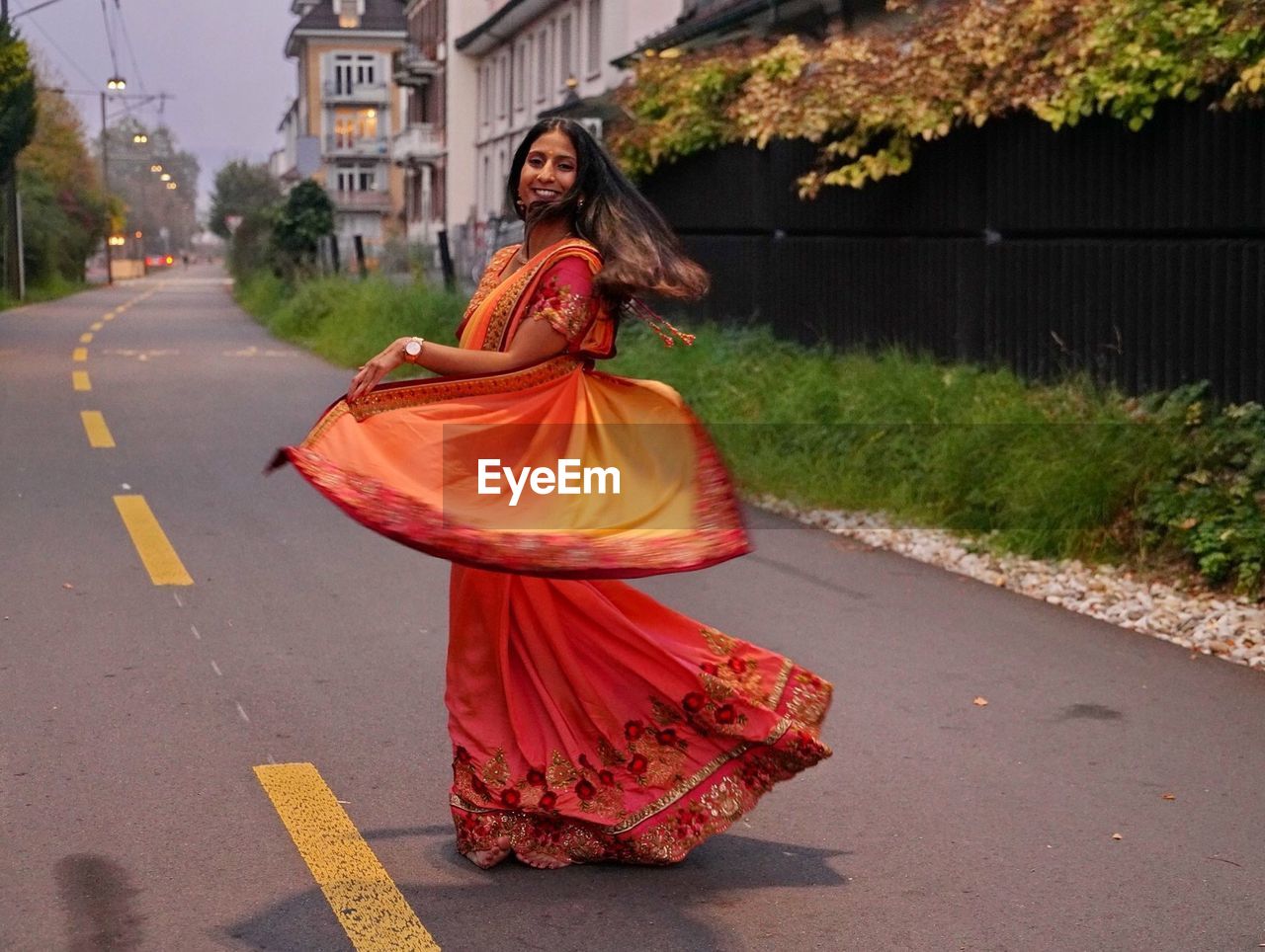 Portrait of smiling woman in sari dancing on road