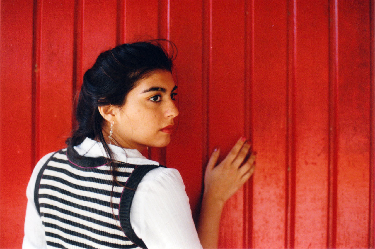 Young woman against red fence