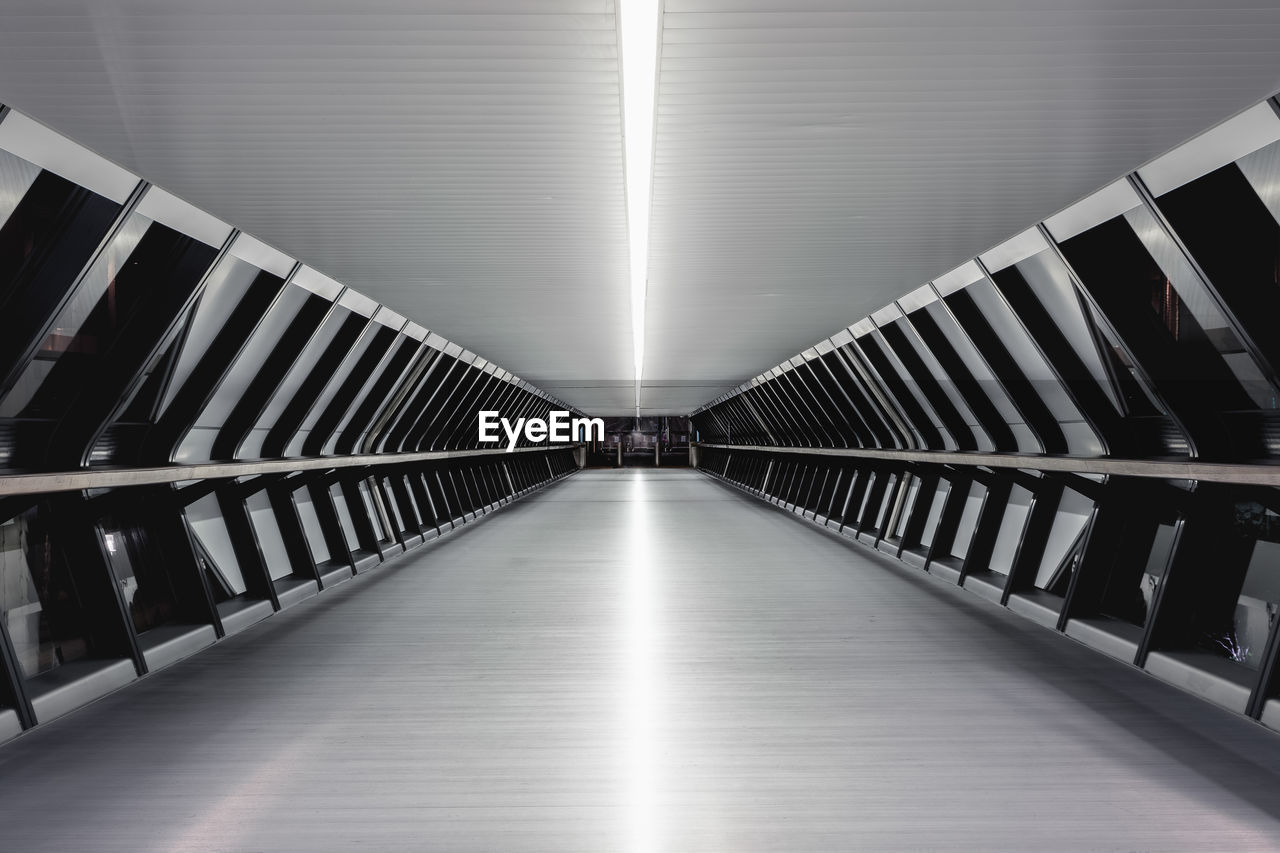 EMPTY CORRIDOR ALONG ILLUMINATED BUILDING