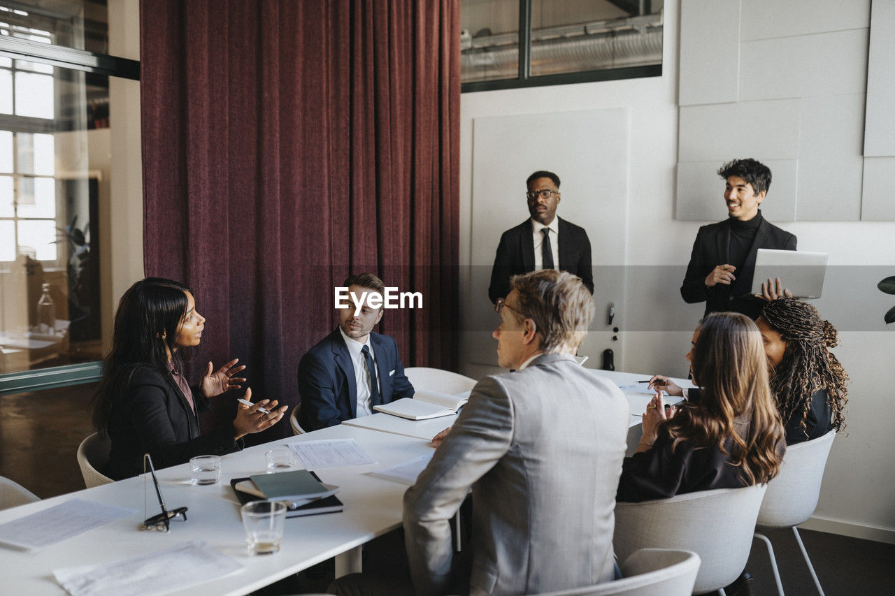 Female entrepreneur discussing with colleagues in business meeting at office