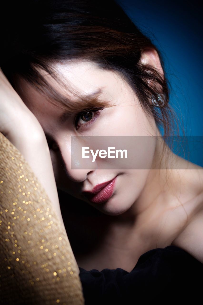 Close-up portrait of beautiful woman against blue background