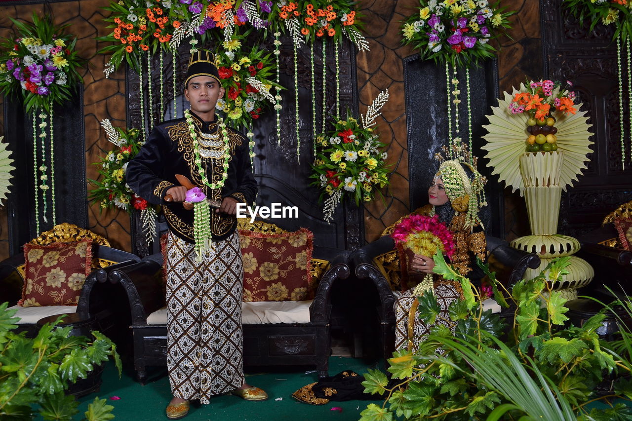 Wedding couple on stage amidst flower decoration