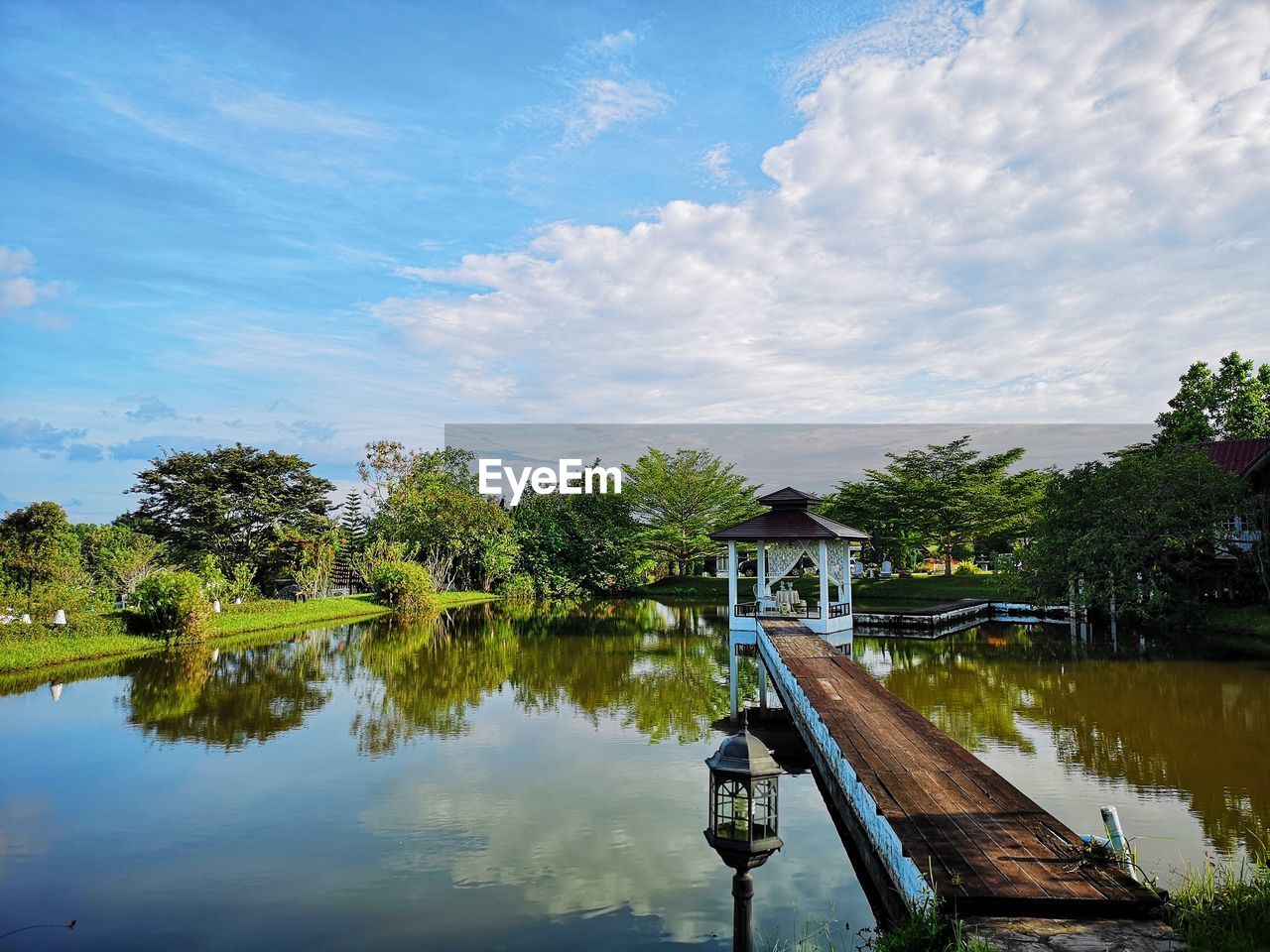 Scenic view of lake by trees and building against sky