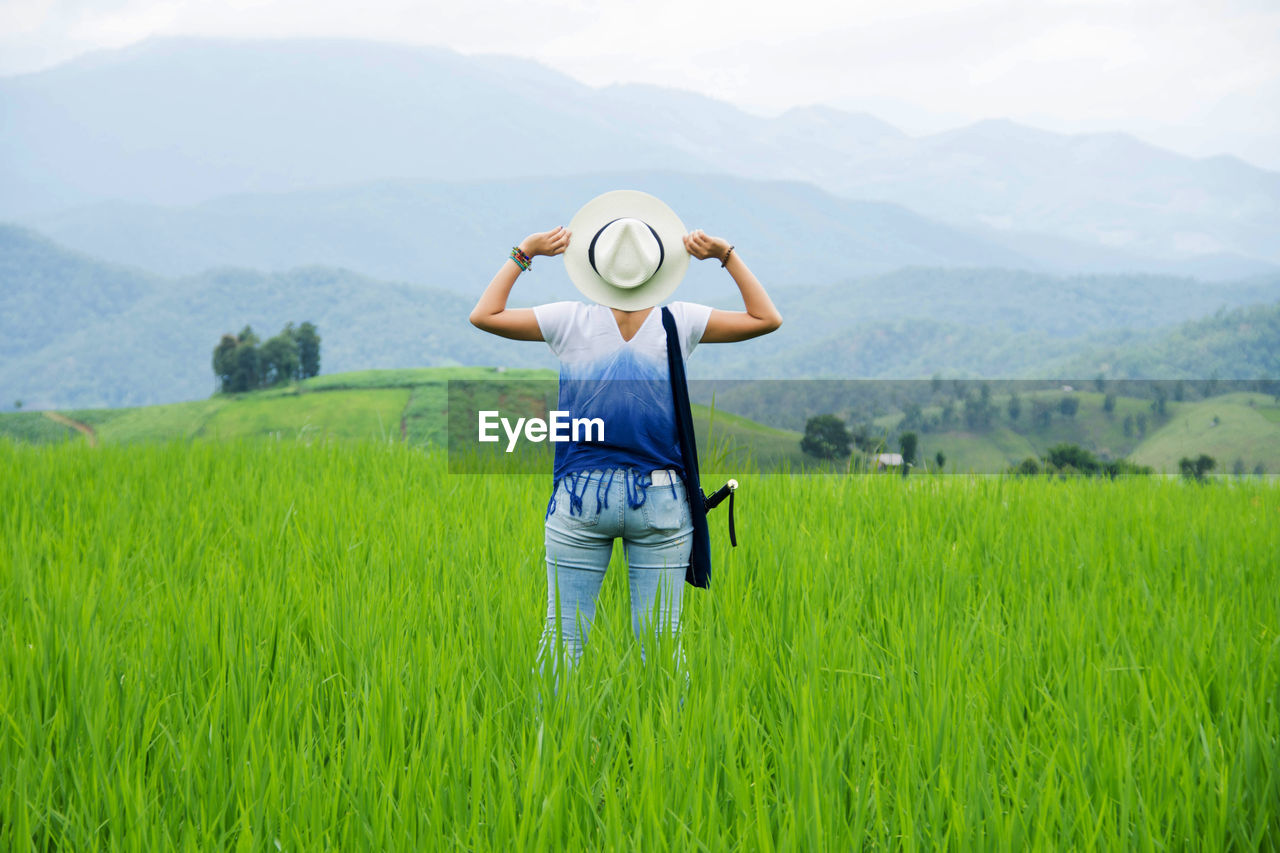 Rear view of a woman standing in field