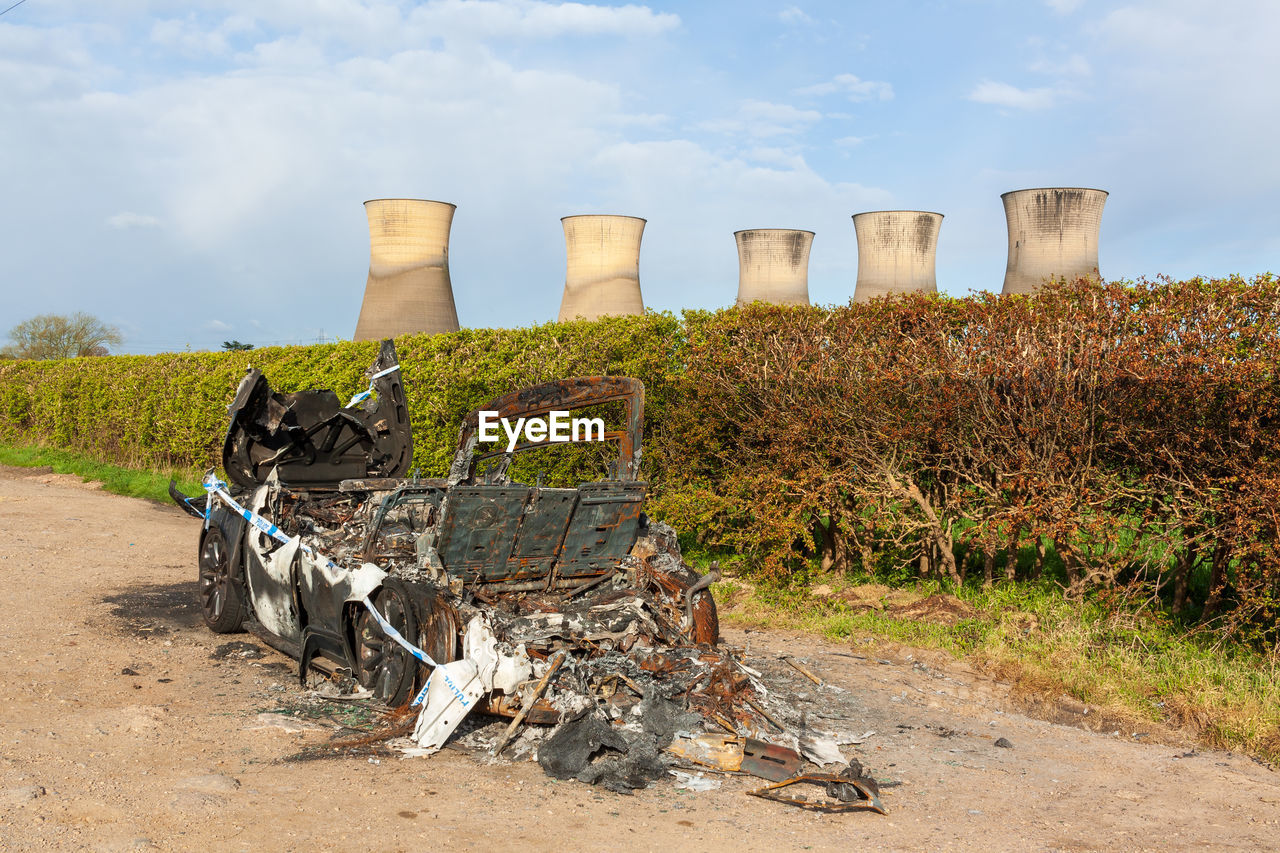 A burned out car in a layby near willington derbyshire with disused colling towers in background.