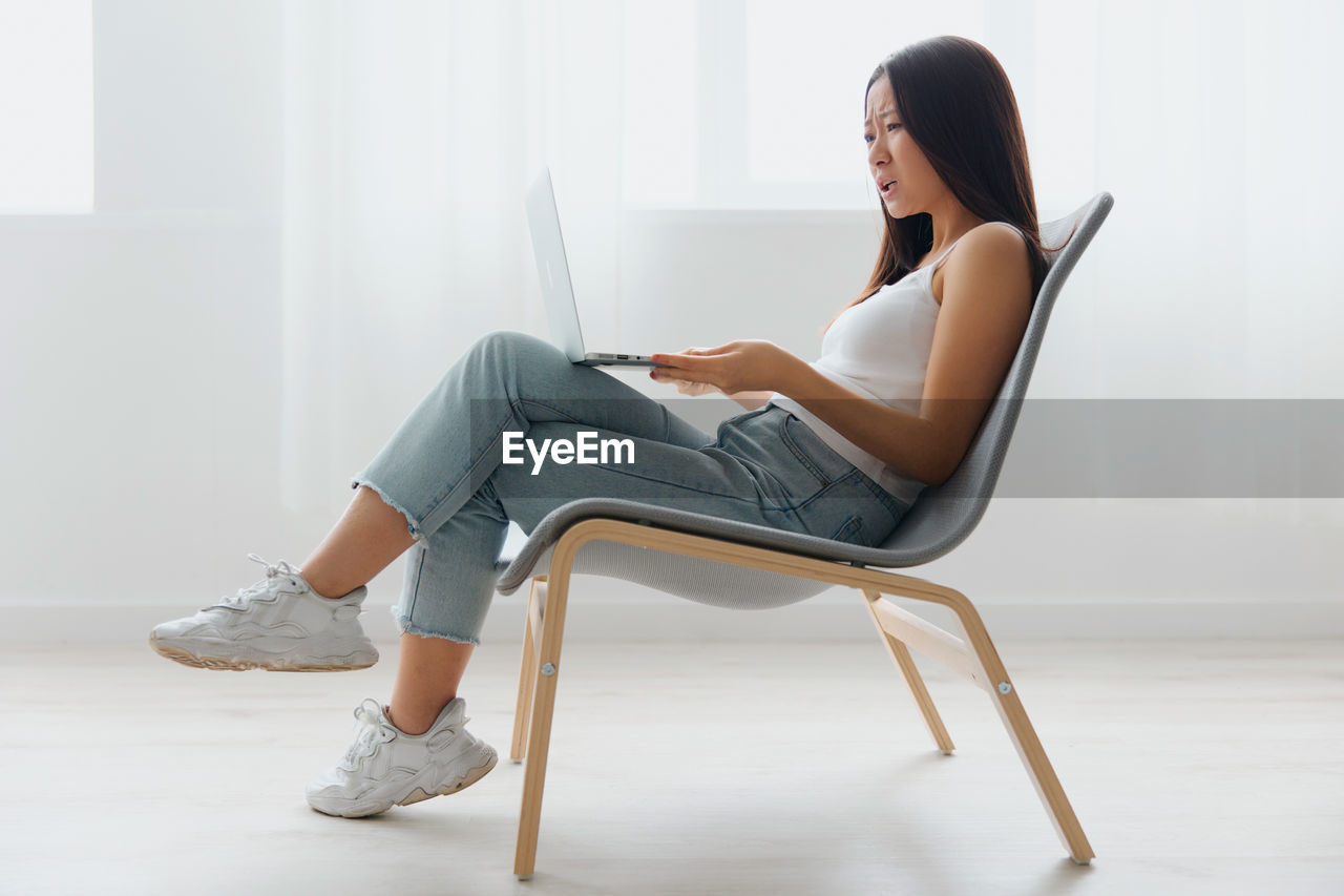 Young woman with laptop sitting on chair