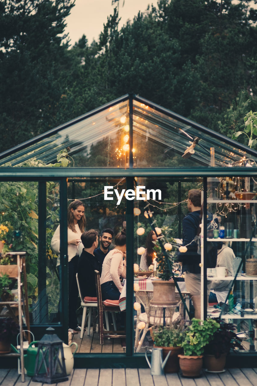 Happy young multi-ethnic group enjoying dinner party in conservatory at back yard