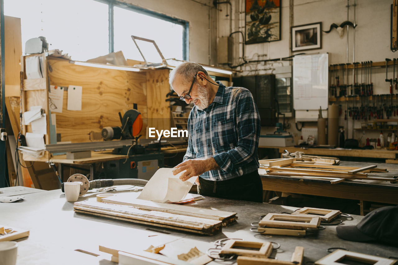 Craftsman examining documents at carpentry workshop