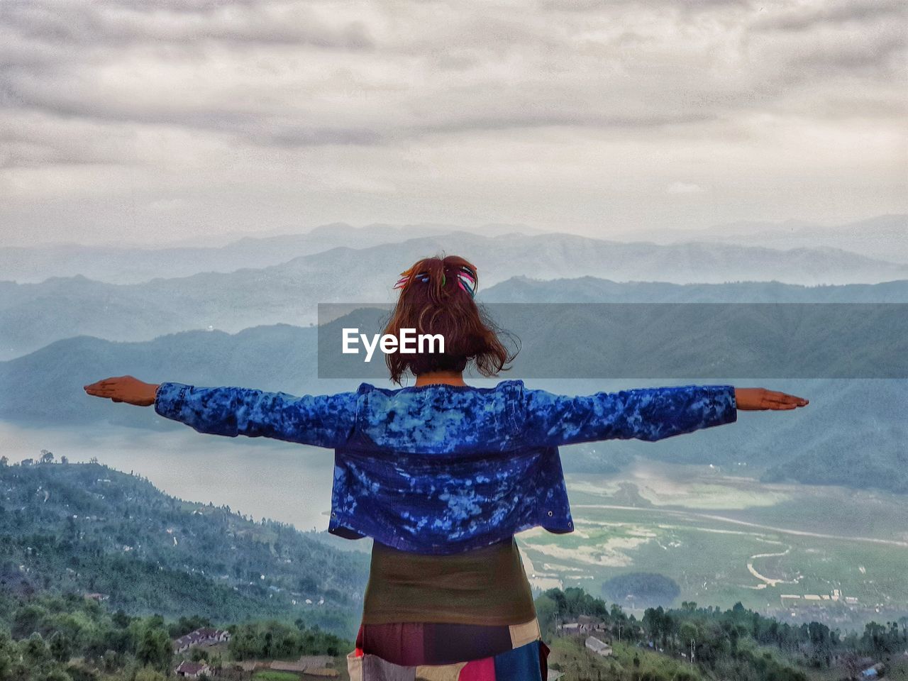 Rear view of woman with arms outstretched looking at landscape