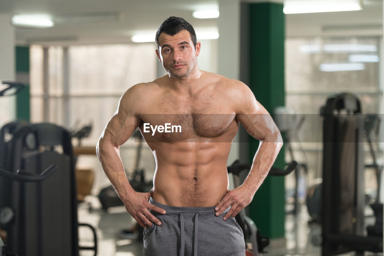 FULL LENGTH OF SHIRTLESS MAN STANDING IN KITCHEN