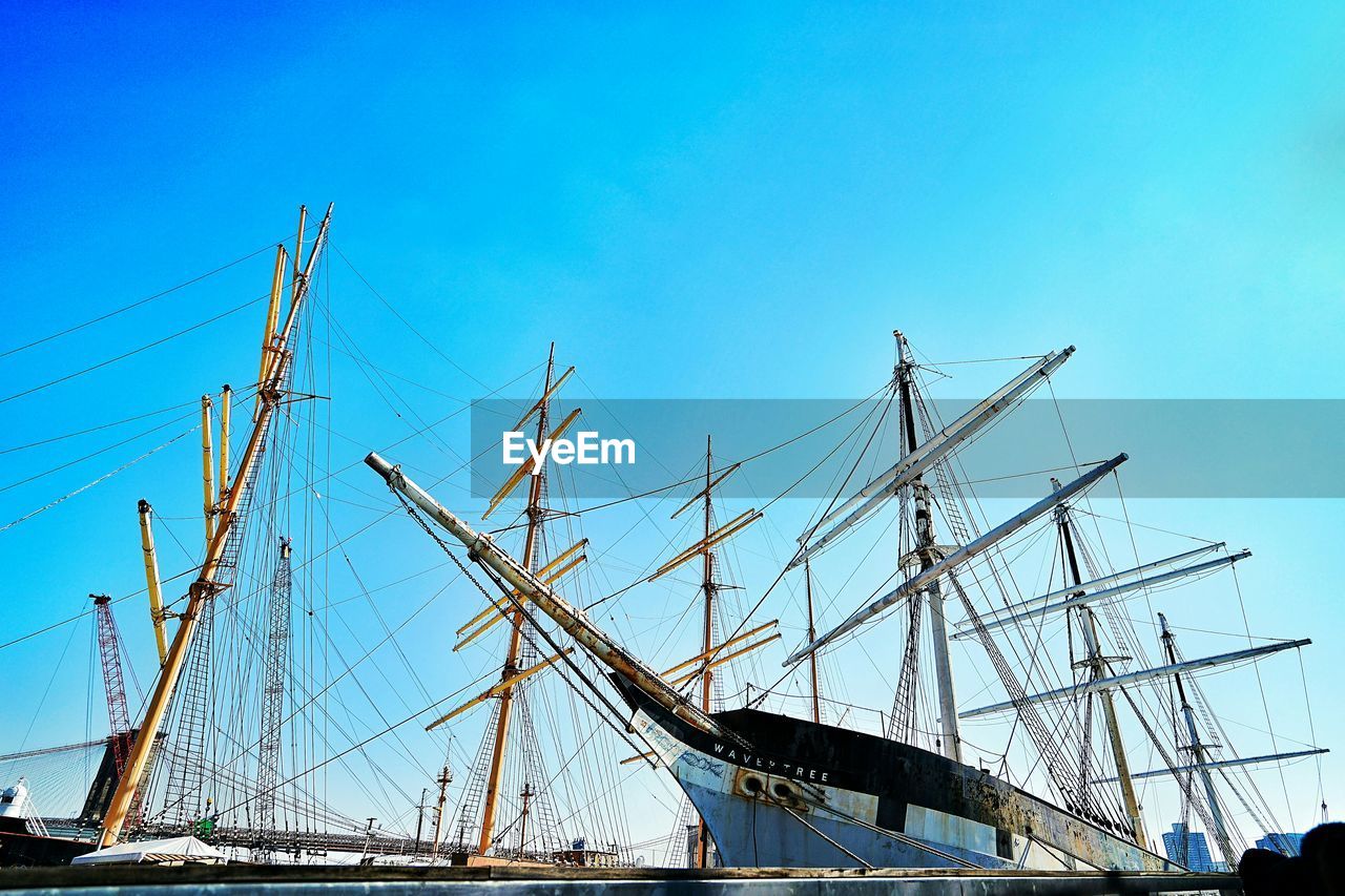 Low angle view of mast on boats moored at harbor against sky