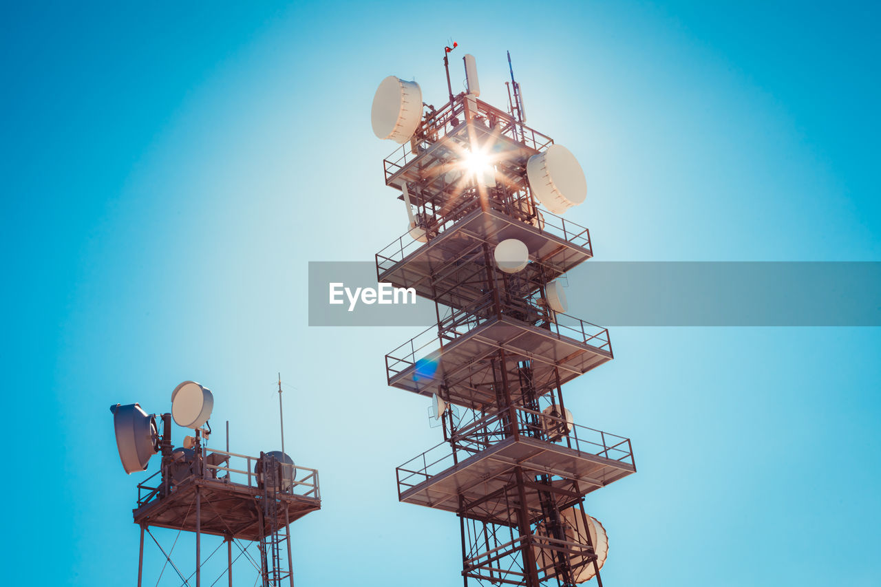 Low angle view of communications tower against clear blue sky