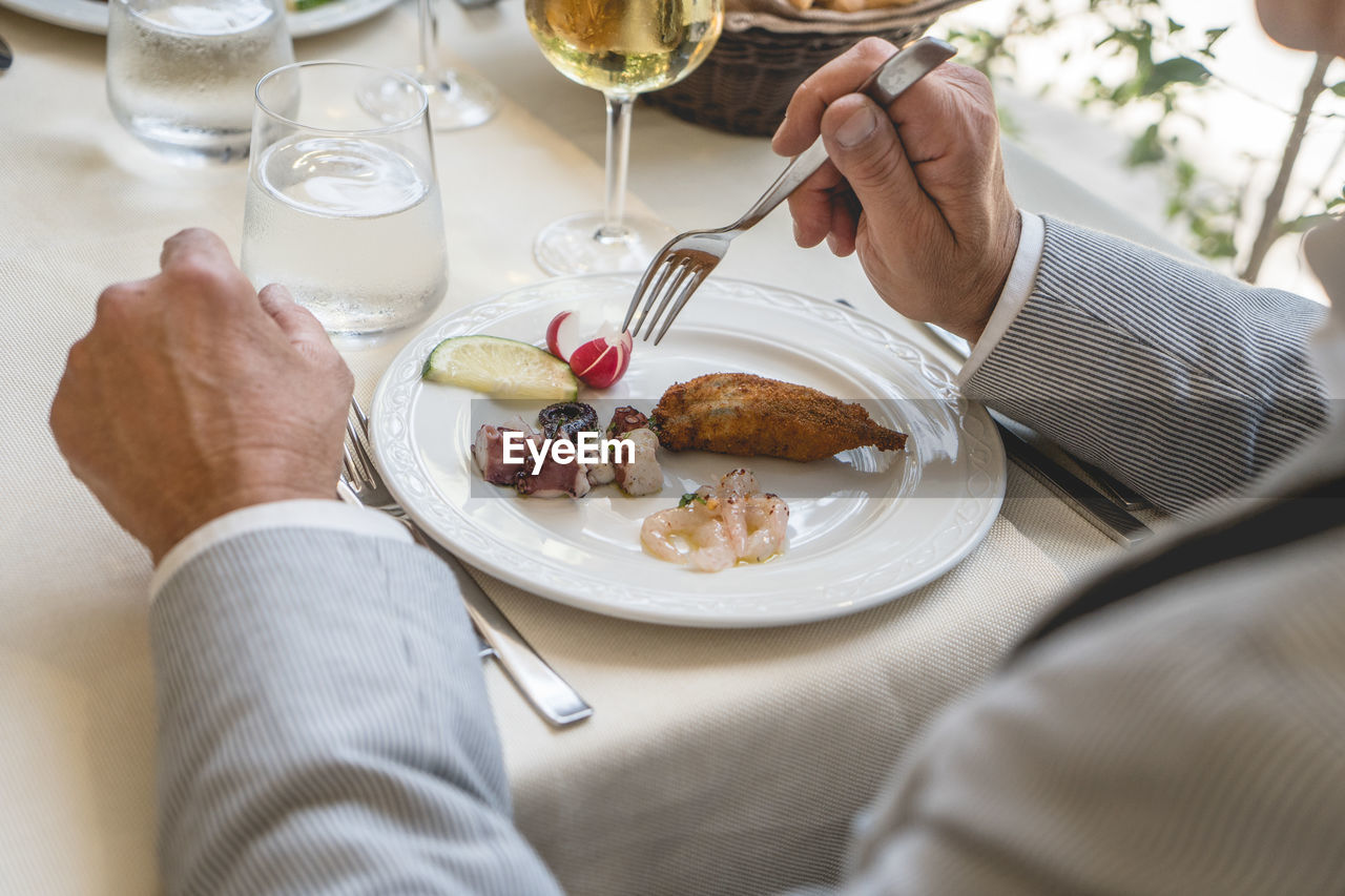 Gentlemen eating fish food, man's hands with business suit preparing to eat a seafood appetizers