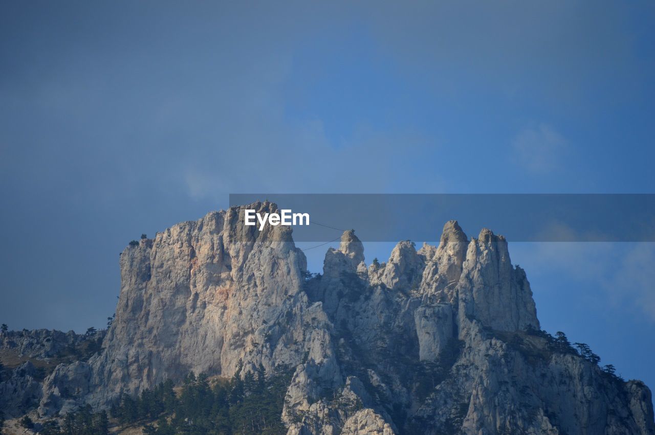 Low angle view of rocky mountains against sky