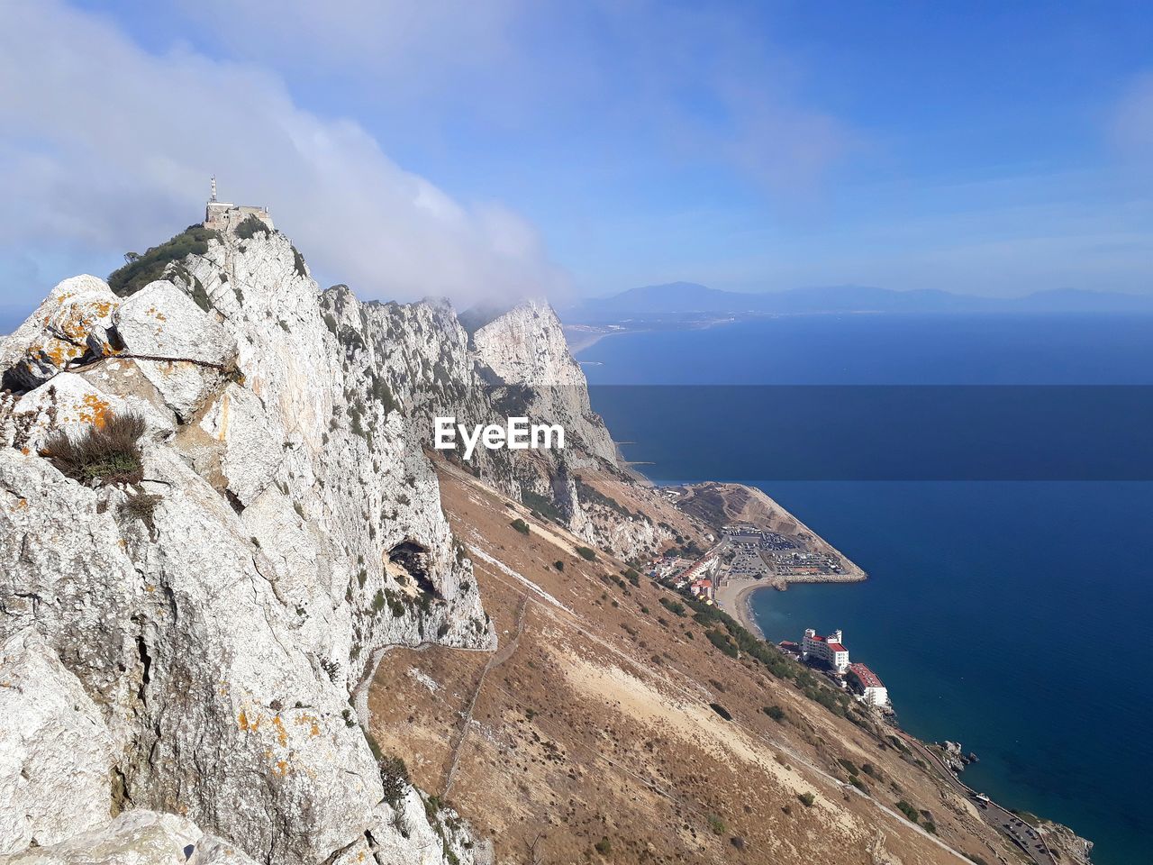 People on rock by mountain against sky