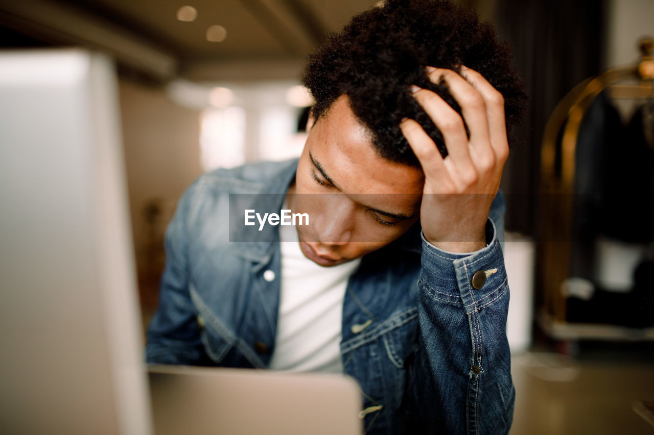 Tired male business executive holding his head while sitting in workplace